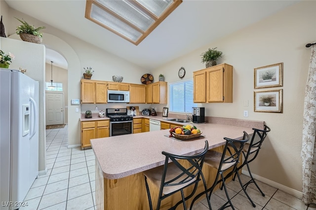 kitchen with white appliances, sink, a kitchen bar, kitchen peninsula, and lofted ceiling