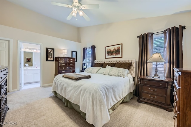 bedroom with ensuite bath, light colored carpet, and ceiling fan