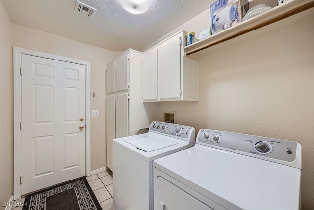 laundry room with cabinets, independent washer and dryer, a textured ceiling, and light tile patterned floors