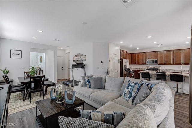 living room with dark wood-style flooring, visible vents, and recessed lighting