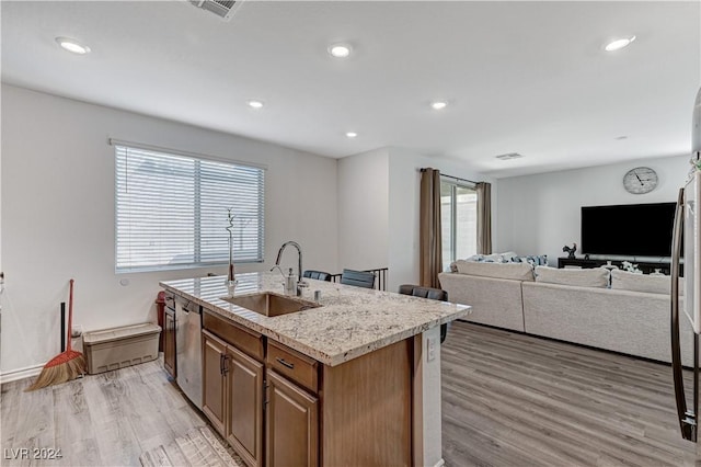 kitchen with dishwasher, light wood-type flooring, a sink, and a center island with sink