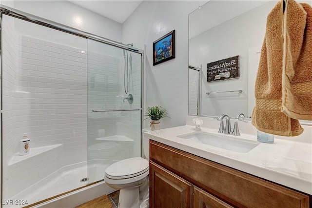 bathroom featuring toilet, vanity, and a shower with door