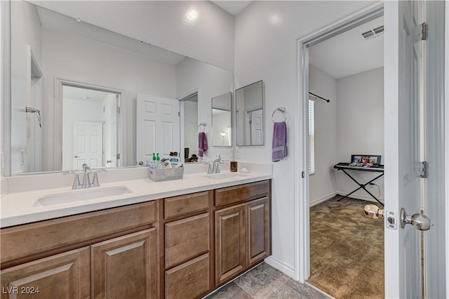 full bath featuring double vanity, a sink, visible vents, and baseboards