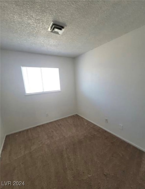 empty room featuring dark carpet and a textured ceiling