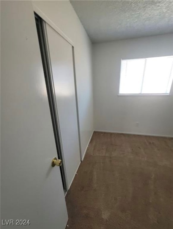 empty room with dark carpet and a textured ceiling