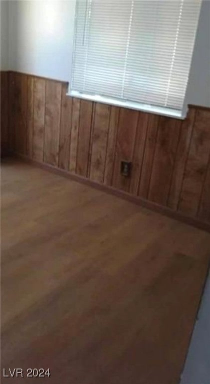 empty room with wood walls and hardwood / wood-style floors