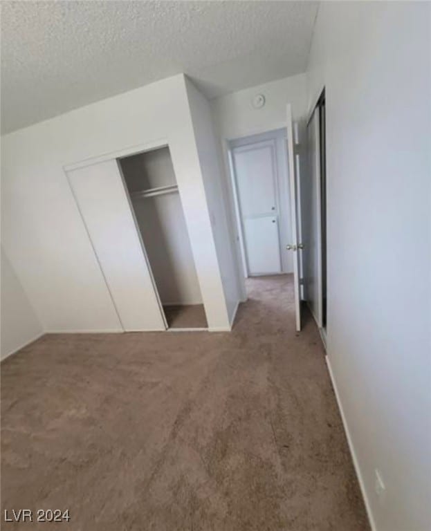 unfurnished bedroom featuring carpet floors, a closet, and a textured ceiling