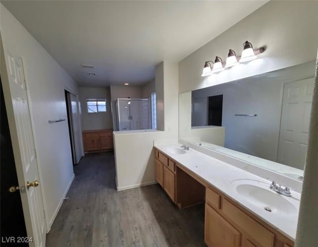 bathroom with hardwood / wood-style floors, a shower with shower door, and vanity