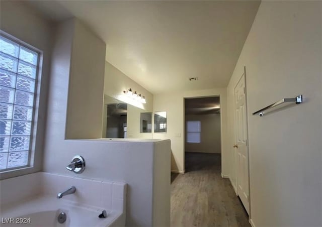 bathroom with a tub to relax in and hardwood / wood-style floors