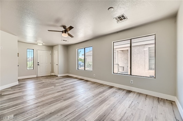 empty room featuring ceiling fan, light hardwood / wood-style floors, and a textured ceiling