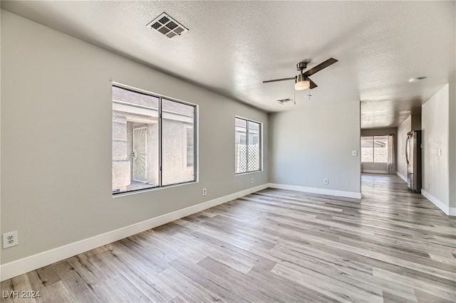 spare room with ceiling fan, light hardwood / wood-style flooring, and a textured ceiling