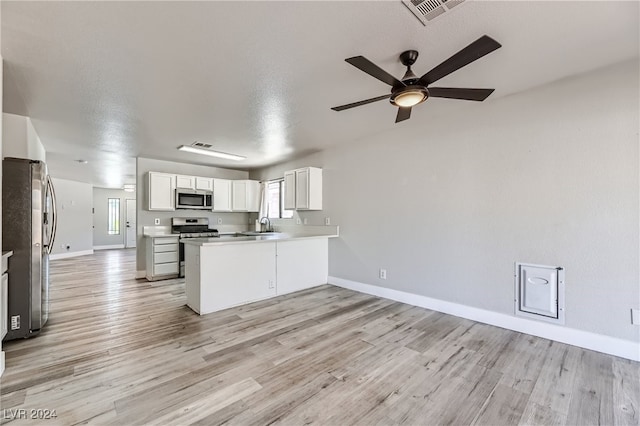 kitchen with stainless steel appliances, kitchen peninsula, light hardwood / wood-style flooring, and white cabinetry