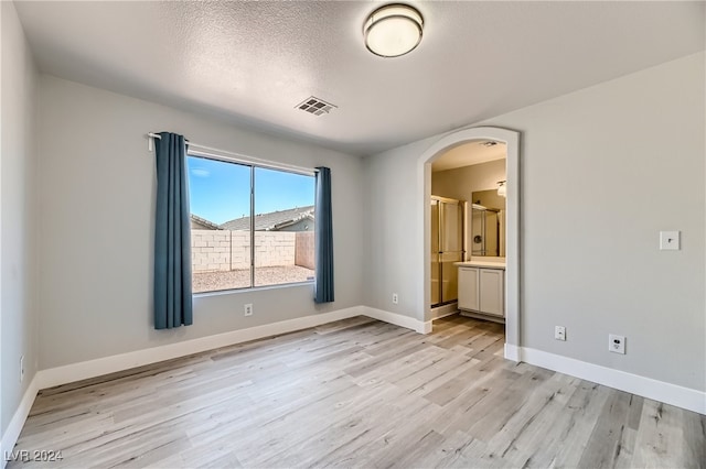 spare room featuring light wood-type flooring and a textured ceiling