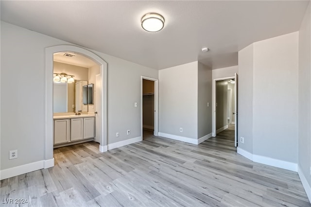 unfurnished bedroom featuring light wood-type flooring, connected bathroom, and sink