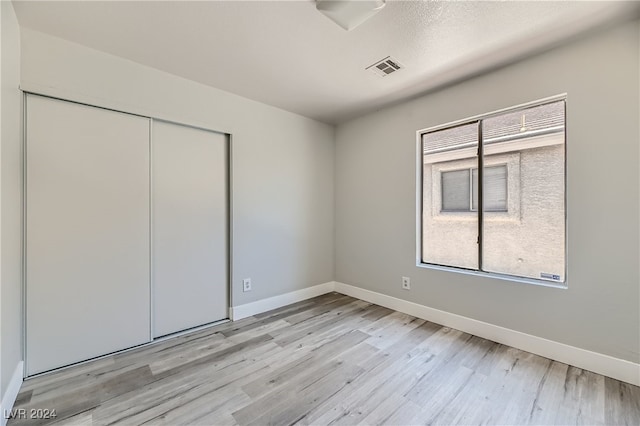 unfurnished bedroom with a closet, light hardwood / wood-style floors, and multiple windows