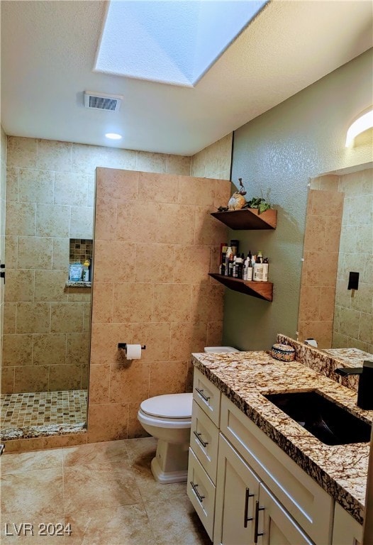 bathroom with vanity, toilet, and a tile shower