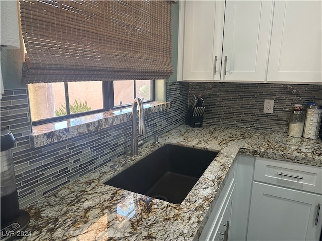 kitchen featuring light stone counters, tasteful backsplash, white cabinetry, and sink