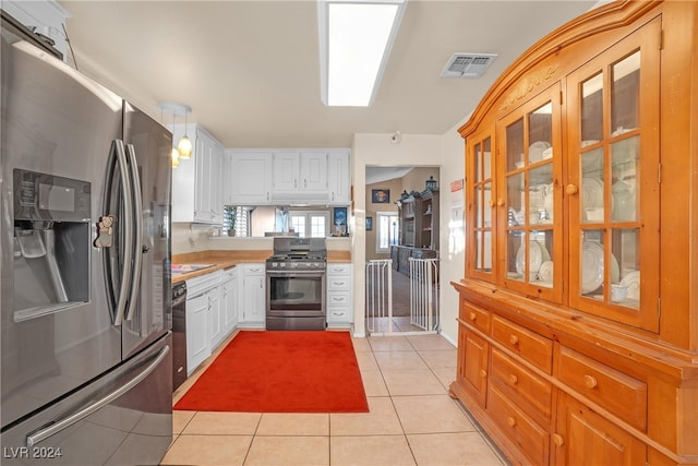 kitchen featuring white cabinets, light tile patterned floors, hanging light fixtures, and appliances with stainless steel finishes