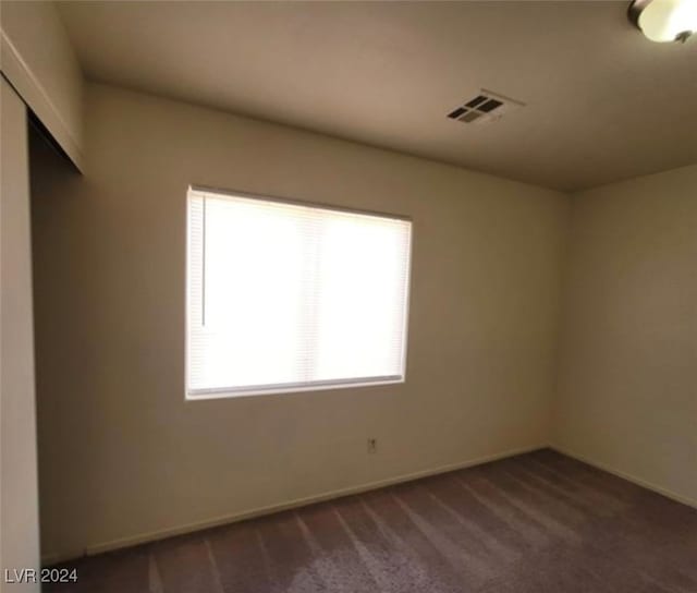 unfurnished room featuring dark carpet