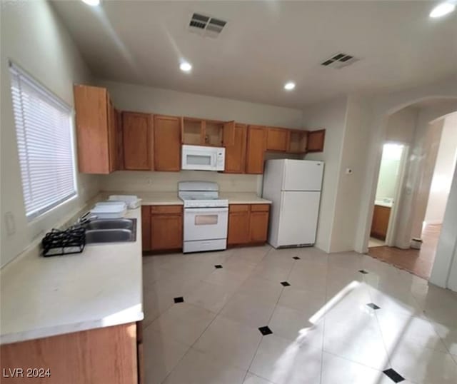 kitchen with white appliances, sink, and light tile patterned floors