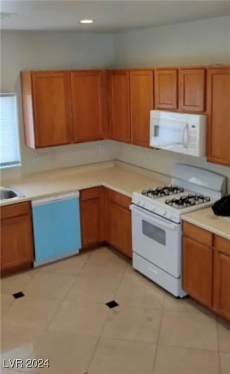 kitchen featuring light tile patterned flooring, white appliances, and sink