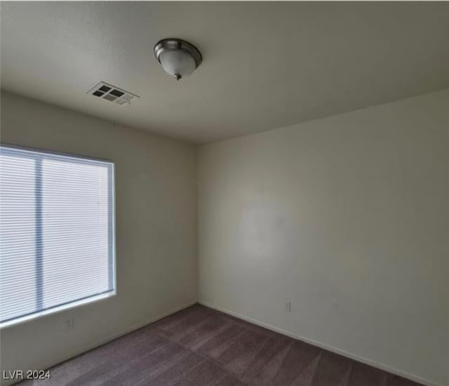 spare room featuring dark colored carpet and a healthy amount of sunlight