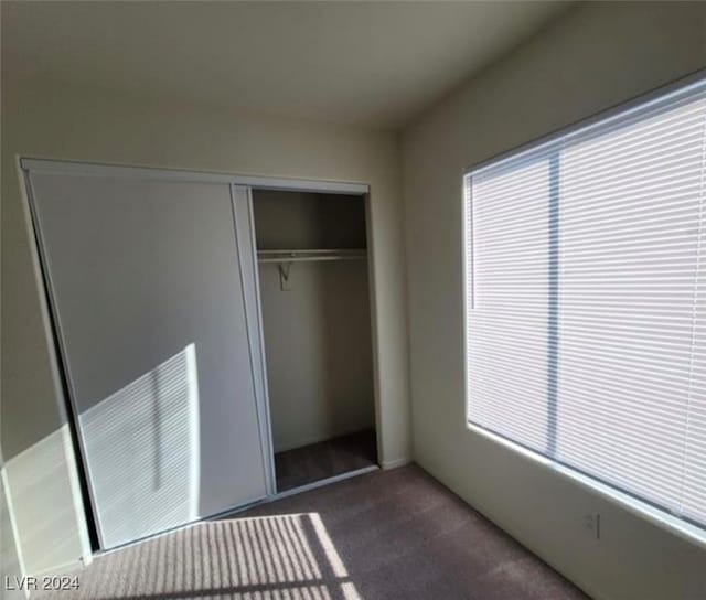 unfurnished bedroom with a closet and dark carpet