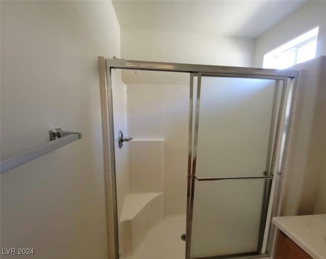 bathroom with a shower with shower door and vanity