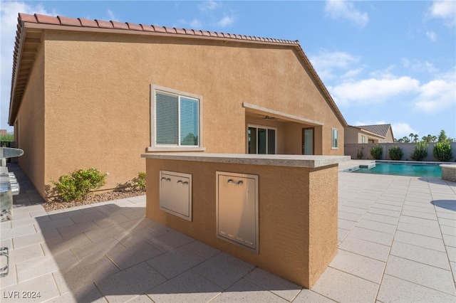 rear view of property with a fenced in pool and a patio