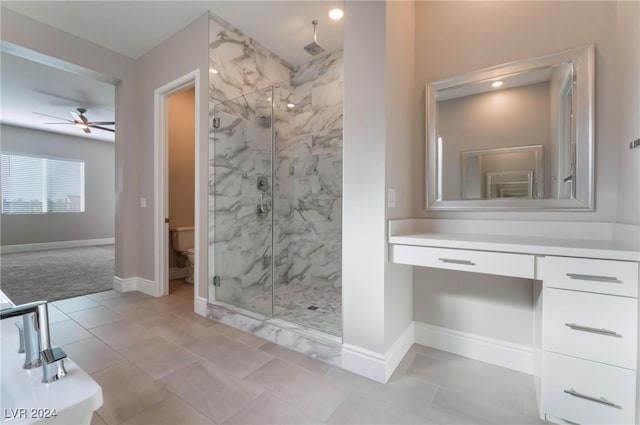 bathroom featuring a shower with door, vanity, ceiling fan, and toilet