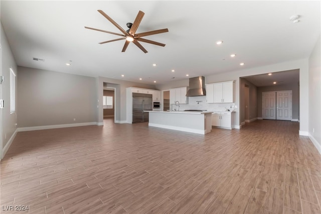 unfurnished living room featuring ceiling fan, sink, and light wood-type flooring