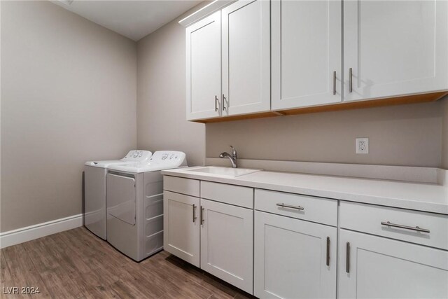 washroom featuring hardwood / wood-style flooring, cabinets, separate washer and dryer, and sink