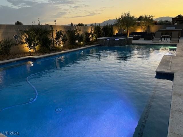 pool at dusk with an in ground hot tub