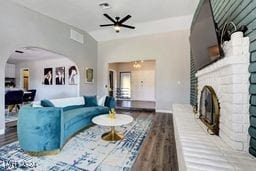 living room with wood-type flooring, a fireplace, and ceiling fan