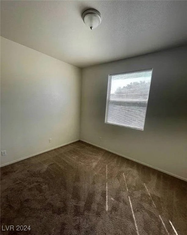 spare room featuring dark carpet