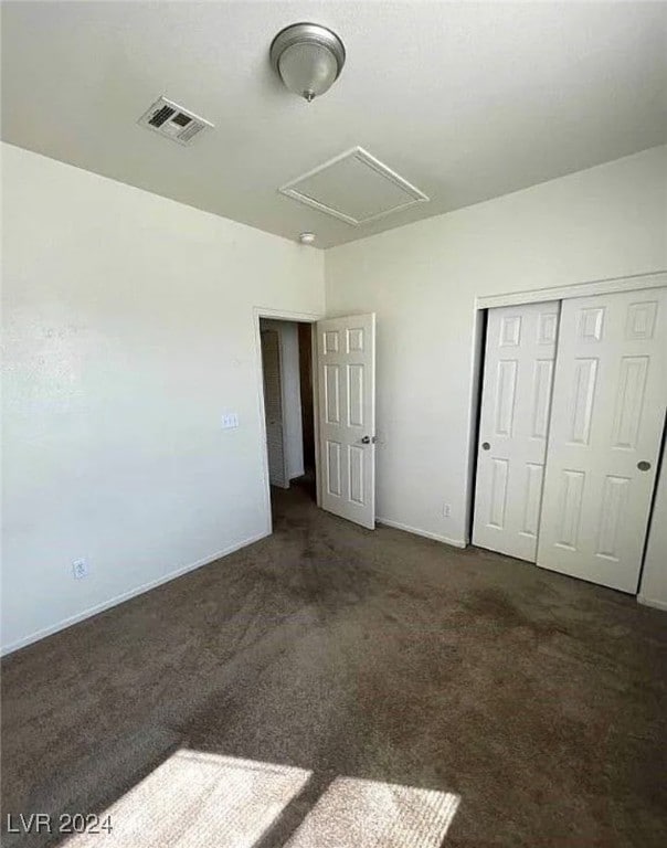 unfurnished bedroom featuring a closet and dark colored carpet