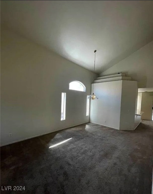 unfurnished living room with lofted ceiling and dark carpet