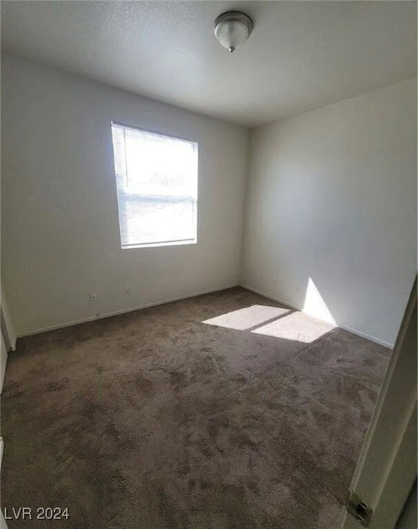 spare room featuring dark carpet