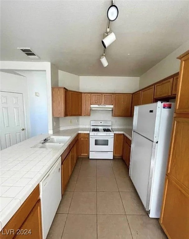 kitchen with tile countertops, white appliances, sink, and light tile patterned floors