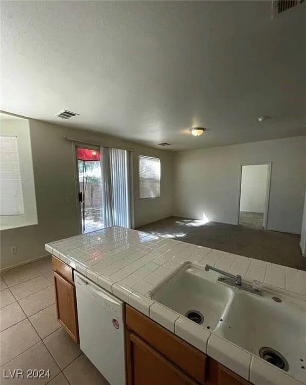 kitchen featuring dishwasher, tile countertops, sink, and light tile patterned flooring