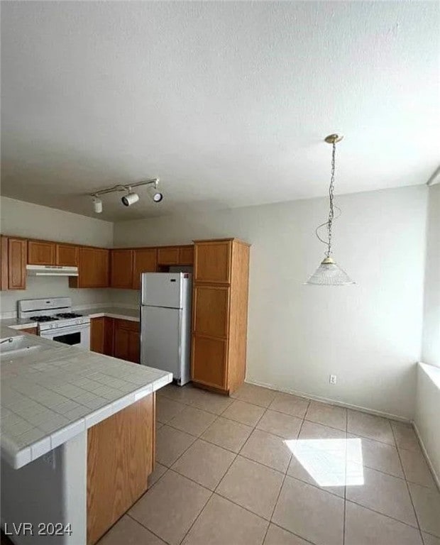 kitchen with white appliances, kitchen peninsula, tile counters, decorative light fixtures, and light tile patterned floors