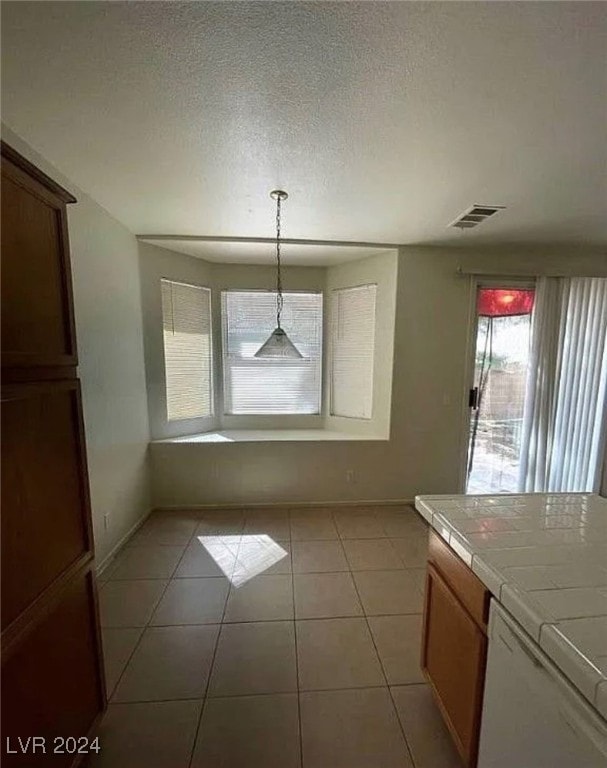 unfurnished dining area featuring light tile patterned flooring and a textured ceiling