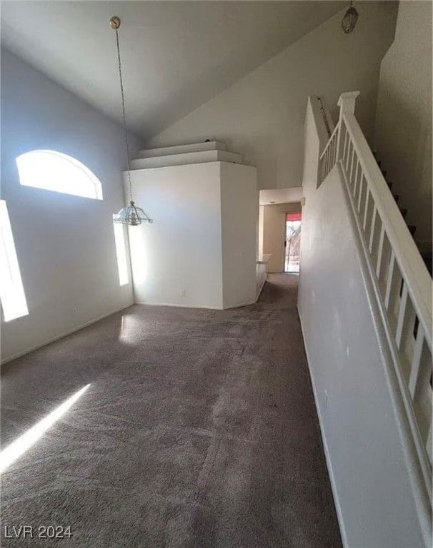 unfurnished living room with dark colored carpet and high vaulted ceiling