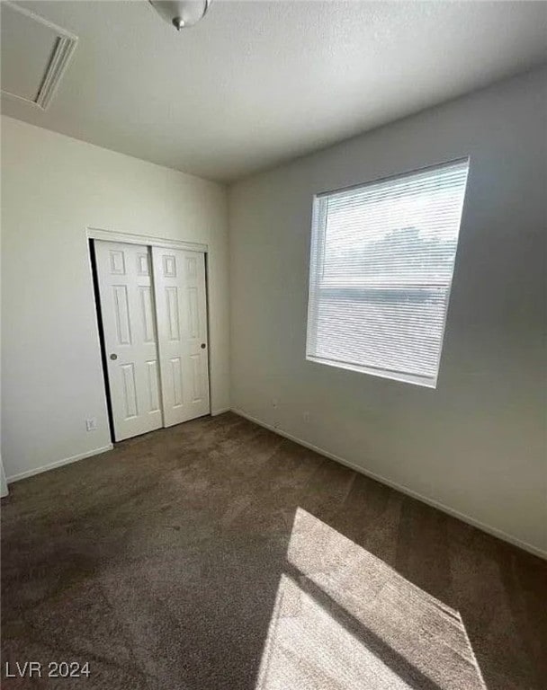 unfurnished bedroom featuring a closet and dark carpet