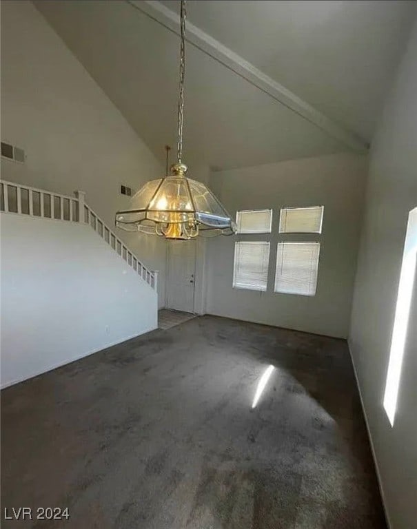 unfurnished dining area with high vaulted ceiling, dark colored carpet, and a chandelier