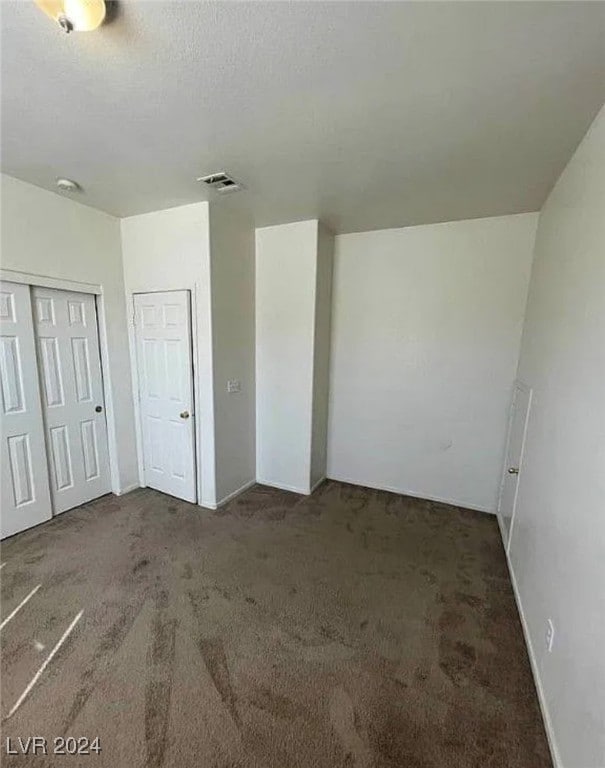 unfurnished bedroom with a closet and dark colored carpet