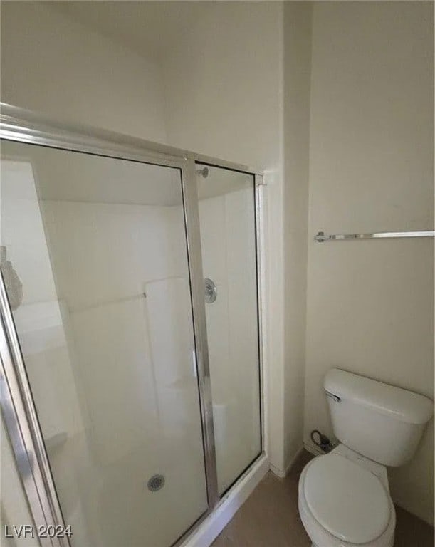 bathroom with a shower with door and toilet