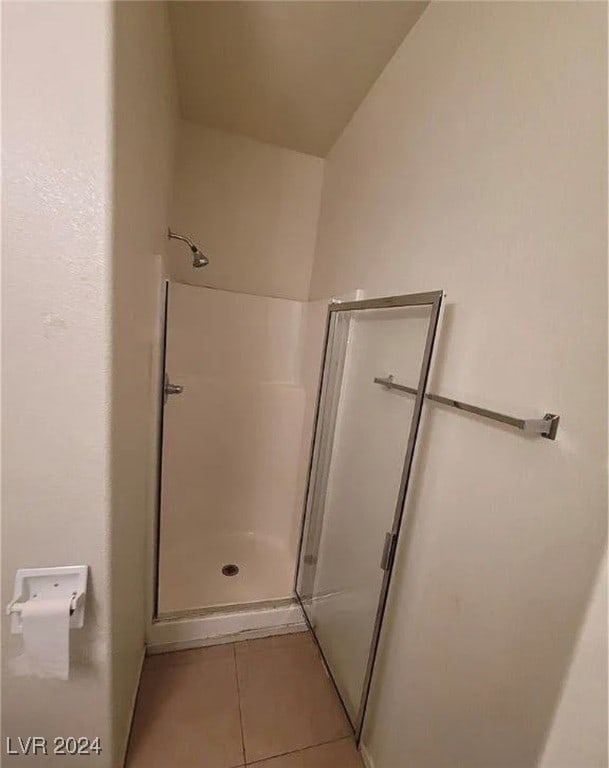 bathroom featuring lofted ceiling, a shower with shower door, and tile patterned flooring