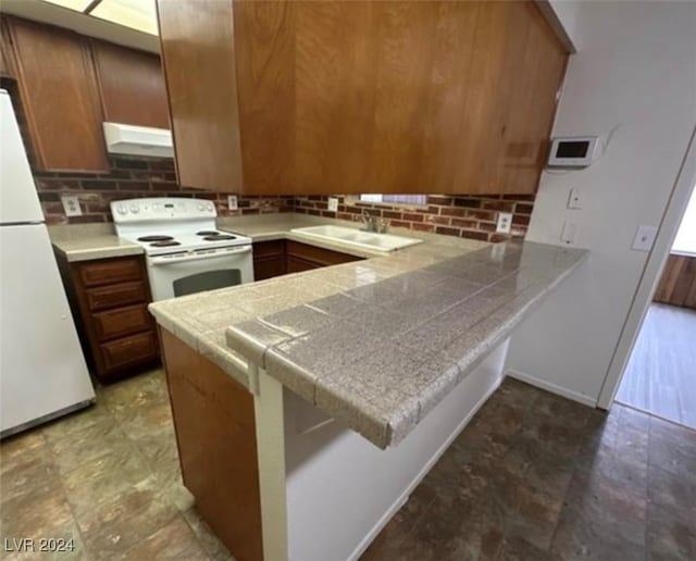 kitchen featuring kitchen peninsula, sink, white appliances, and decorative backsplash