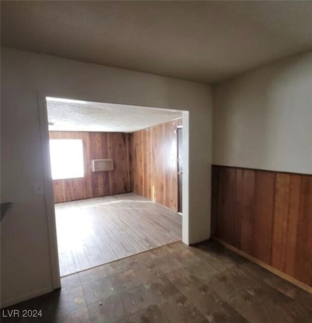 spare room featuring wood walls and dark hardwood / wood-style floors